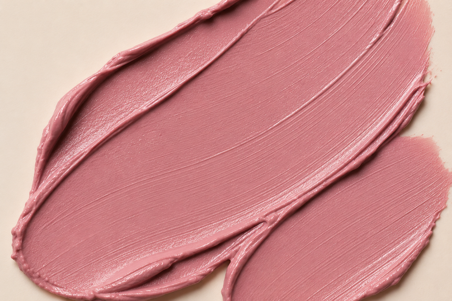 A close-up of a dusty rose pink cosmetic cream swatch, showing the thick, creamy texture and smooth swipe strokes on a light beige background.